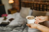 Kaboompics - Hands Holding Morning Coffee Beside Bed, Cozy Bedroom Lifestyle