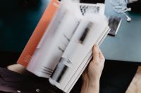 Kaboompics - Person Flipping Through an Orange-Covered Magazine
