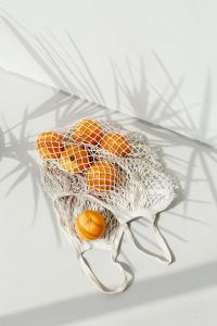 Kaboompics - Overhead Orange Bag Still Life with Sharp Palm Leaf Shadows on White