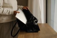 Kaboompics - Hands Placing Closed Laptop Into Black Leather Work Bag