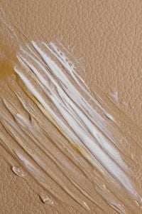 Kaboompics - Diagonal White Skincare Cream Streaks on a Warm Tan Textured Background