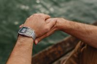 Kaboompics - Clasped Hands Wearing a Retro Calculator Watch over Water, Lakeside Close-Up