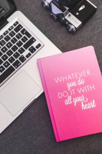 Pink notebook with a silver laptop and a camera