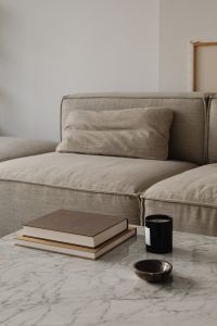 Kaboompics - Beige Sofa with Stacked Art Books and Candle on Marble Table