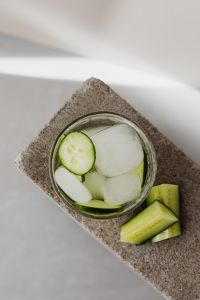 Kaboompics - Top-Down Cucumber and Lime Detox Water with Ice on a Diagonal Stone Slab, Minimal Vertical Drink Background with Copy Space
