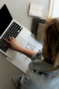 Kaboompics - Hand Working on Laptop beside Architectural Floor Plan and Material Samples
