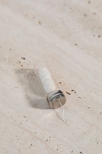 Kaboompics - Glass Dental Floss Dispenser Close-Up on Beige Stone for Sustainable Oral Care
