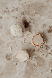Kaboompics - Top-Down Coconut Truffle Halves and Whole Candy on Speckled Pale Stone, Dessert Styling