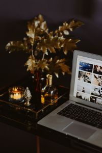Kaboompics - Laptop Workspace with Gold Foliage, Candle and Perfume Bottle