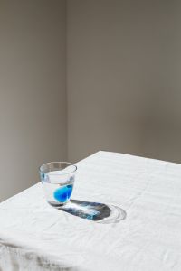 Kaboompics - Blue-Toned Water Glass Casting a Long Sunlit Shadow on White Linen