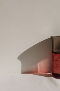 Kaboompics - Red Perfume Bottle Casting a Shadow on a White Surface