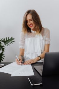 Kaboompics - Smiling Businesswoman Signing Contract at Laptop Desk