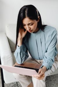 Kaboompics - Asian Woman Taking a Phone Call While Using a Laptop on a Sofa