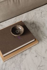Kaboompics - Gold Rings in a Stone Bowl on Stacked Books beside Sofa