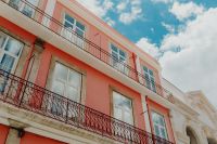 Kaboompics - Looking Up at Salmon-Pink Lisbon Facade with Long Iron Balconies and Blue Sky