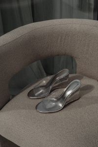 Kaboompics - Silver Transparent High-Heeled Mules on a Curved Gray Chair, Women's Fashion Footwear Editorial