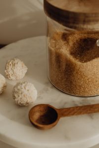 Kaboompics - Wooden Spoon Beside a Glass Jar of Brown Sugar and Coconut Truffles, Marble Kitchen Counter Close-Up