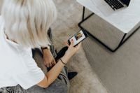 Kaboompics - Close-Up of Woman Using Phone on Sofa Beside Laptop