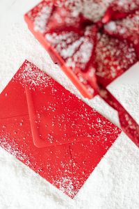 Kaboompics - Close-Up of a Glittered Red Envelope beside a Snowy Christmas Gift Box