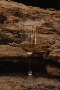 Kaboompics - Single Glass of White Wine Against Dark Coastal Rocks