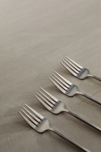 Kaboompics - Matte Steel Forks Diagonal Flat Lay on a Neutral Textured Surface