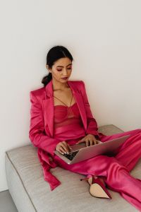 Asian Businesswoman Working on Laptop in Pink Satin Suit