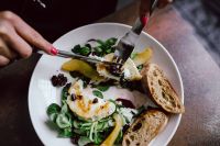 Kaboompics - Hands Slicing Goat Cheese Salad with Pear, Greens, Dried Cranberries and Bread