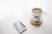 Kaboompics - White Smartphone and Wolf-Print Coffee Mug on Wooden Coaster, Minimal Work Break Still Life