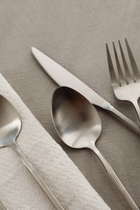 Kaboompics - Close-Up Matte Steel Spoon, Knife and Fork beside Textured Napkin