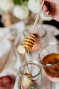 Kaboompics - Honey Dipper Close-Up with Fruit Jars on Linen