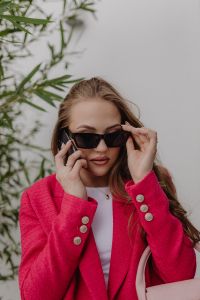 Kaboompics - Woman Adjusting Black Sunglasses in a Fuchsia Blazer