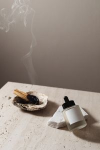 Kaboompics - Skincare Serum Bottle with Incense Smoke and Shell Dish on Travertine