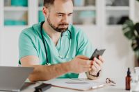 Kaboompics - Doctor Checking Smartphone Beside Medical Supplies