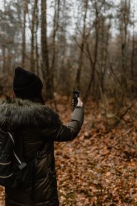 Kaboompics - A woman takes a picture with her iPhone X in the autumn forest