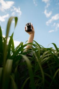 Kaboompics - Holding A Vintage Camera Above Tall Green Grass