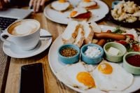 Kaboompics - Breakfast Spread with Eggs, Sausages, Cappuccino and Laptop