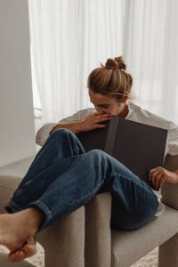 Kaboompics - Close-Up of Woman Reading a Book in a Neutral Armchair