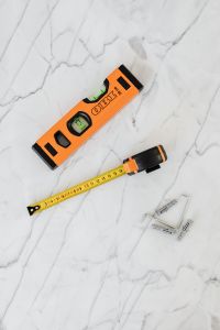 Kaboompics - Vertical Renovation Tool Arrangement with Orange Level, Tape Measure and Metal Wall Anchors