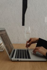 Kaboompics - Close-Up of a Laptop, Wine Glass and Businesswoman's Hand