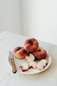Kaboompics - Peach Plate Composition with Whole Fruit and Bright Copy Space