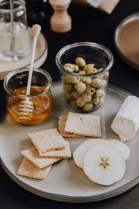 Kaboompics - Healthy Snack Plate with Crispbread, Apple Slices, Green Olives and Honey, Overhead Food Styling