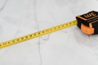 Kaboompics - Yellow Tape Measure and Black-Orange Case on White Marble, Close-Up DIY Tool Background