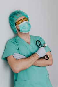 Kaboompics - Young Doctor Looking Up in Yellow-Tinted Protective Glasses and Mask, Healthcare Campaign Image