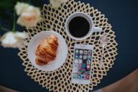Kaboompics - Coffee cup with a croissant and a smartphone on a golden mat