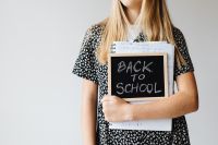 Kaboompics - Teenage Student Holding Back to School Chalkboard and Notebooks