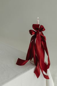Kaboompics - White Candle Wrapped in Red Satin Ribbon on Neutral Background