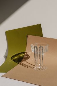 Kaboompics - Glass Perfume Bottle and Earrings on Green and Brown Paper
