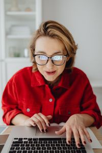 Kaboompics - Smiling Woman Leaning over Notebook at Bright Home Office Desk