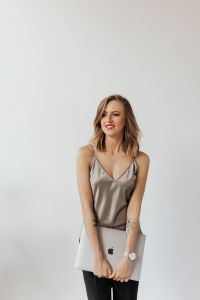Kaboompics - Smiling Woman in Silver Satin Top Holding Laptop in a Studio