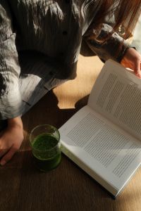 Kaboompics - Woman Reading a Book in Bed with a Green Smoothie